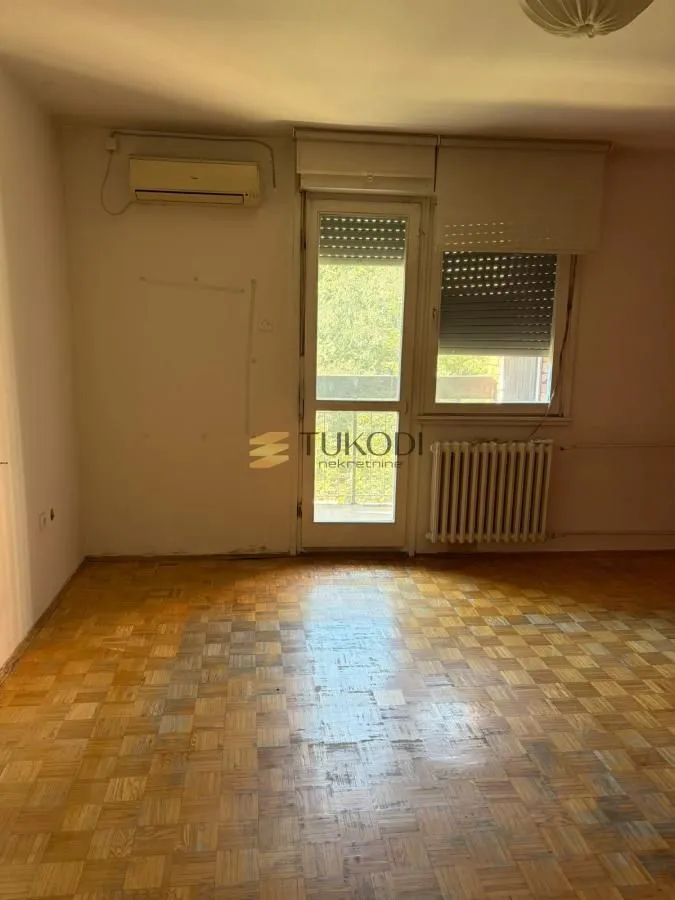 Prazna soba sa parketom i izlazom na terasu.