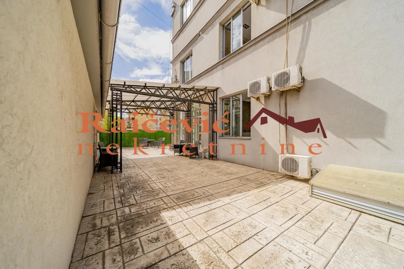Paved courtyard with a canopy and outdoor seating.