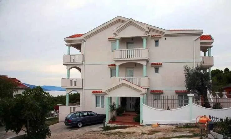 Pogled na prednju fasadu višespratne stambene zgrade sa terasama i dvorištem.