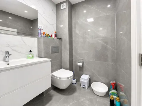 Moderne kupatilo sa bijelim umivaonikom, konzolnom šoljom i sivim pločicama. - image 8