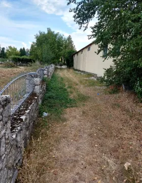 Pogled na dvorište sa kamenom ogradom i zelenilom pored kuće. - image 9