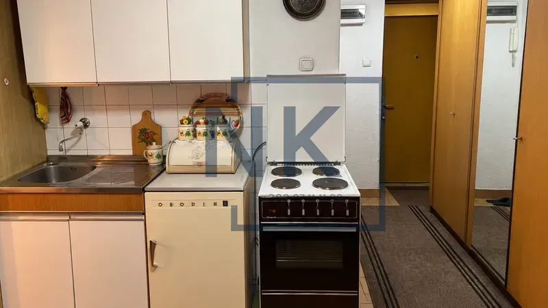 Small kitchen with a sink, stove, and upper cabinets.