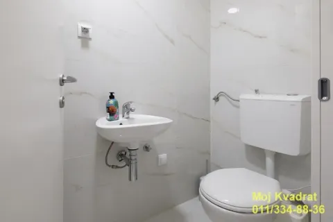 Smaller bathroom with a washbasin and toilet, lined with light marble tiles. - image 7