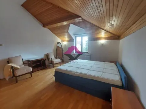 Prostrana spavaća soba u potkrovlju sa drvenim krovnim konstruktivnim elementima i bračnim krevetom. - image 11