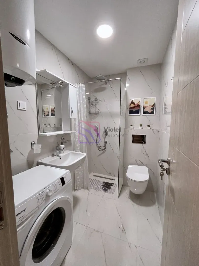 Modernly equipped bathroom with a walk-in shower and washing machine.