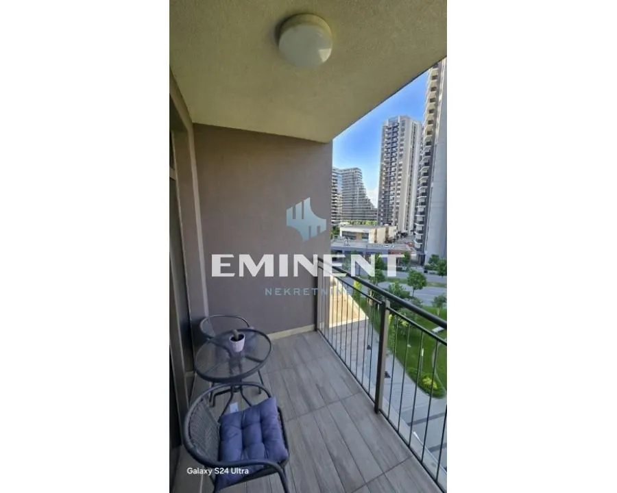 Covered balcony with seating set and a view of the neighborhood and city buildings.