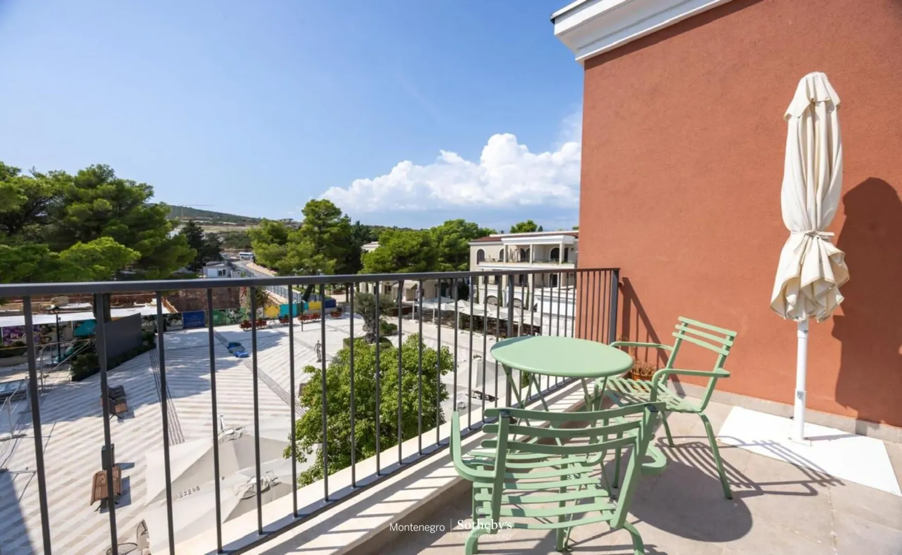 Namješten balkon sa stolom, stolicama i suncobranom i pogledom na okruženje.