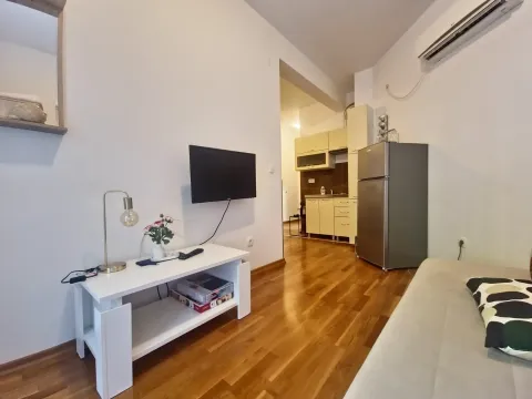 Living room with a TV, a low coffee table, and a view of the kitchen in the background. - image 6