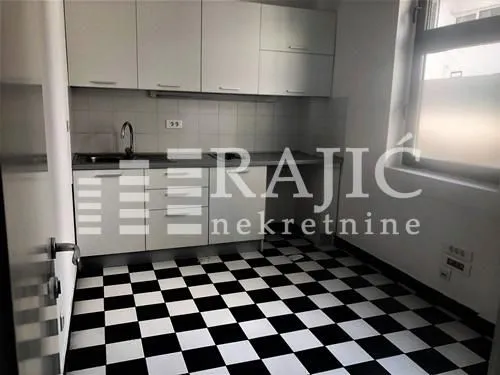 Smaller kitchen with white cabinets and black and white floor tiles.