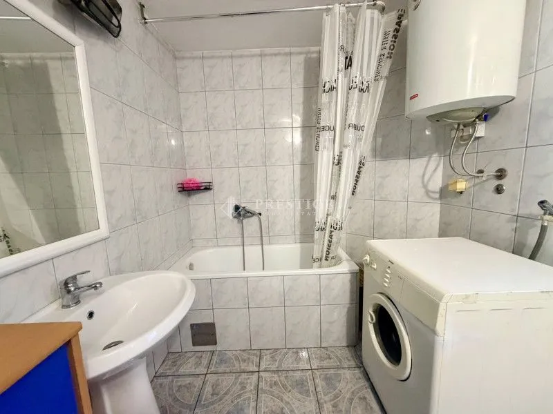 Small bathroom with a bathtub, washbasin, and washing machine.
