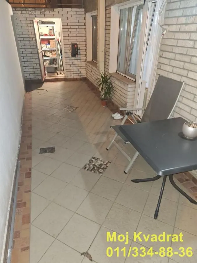 Popločana terasa sa garniturom za sedenje i pogledom na unutrašnje dvorište.