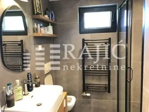 Modern bathroom with a sink, shower cabin, and dark tiles. - image 20