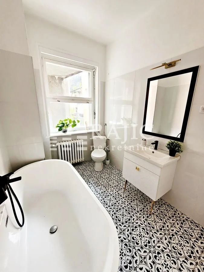 Bright bathroom with a bathtub, vanity, and toilet.