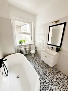 Bright bathroom with a bathtub, vanity, and toilet. - image 17