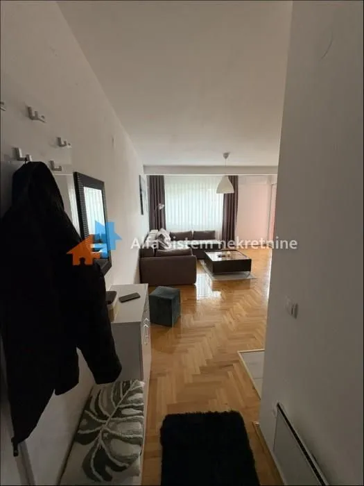 Pogled iz hodnika na dnevnu sobu sa garniturom i parketom.