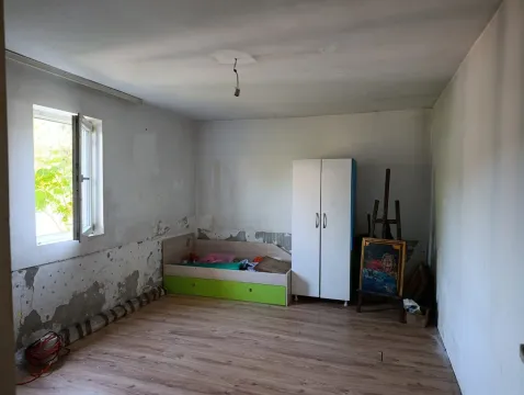 Nenameštena spavaća soba sa krevetom, ormanom i oštećenim zidovima. - image 6