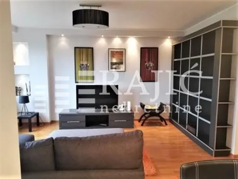 Living room with sofa, TV unit and a large bookshelf.