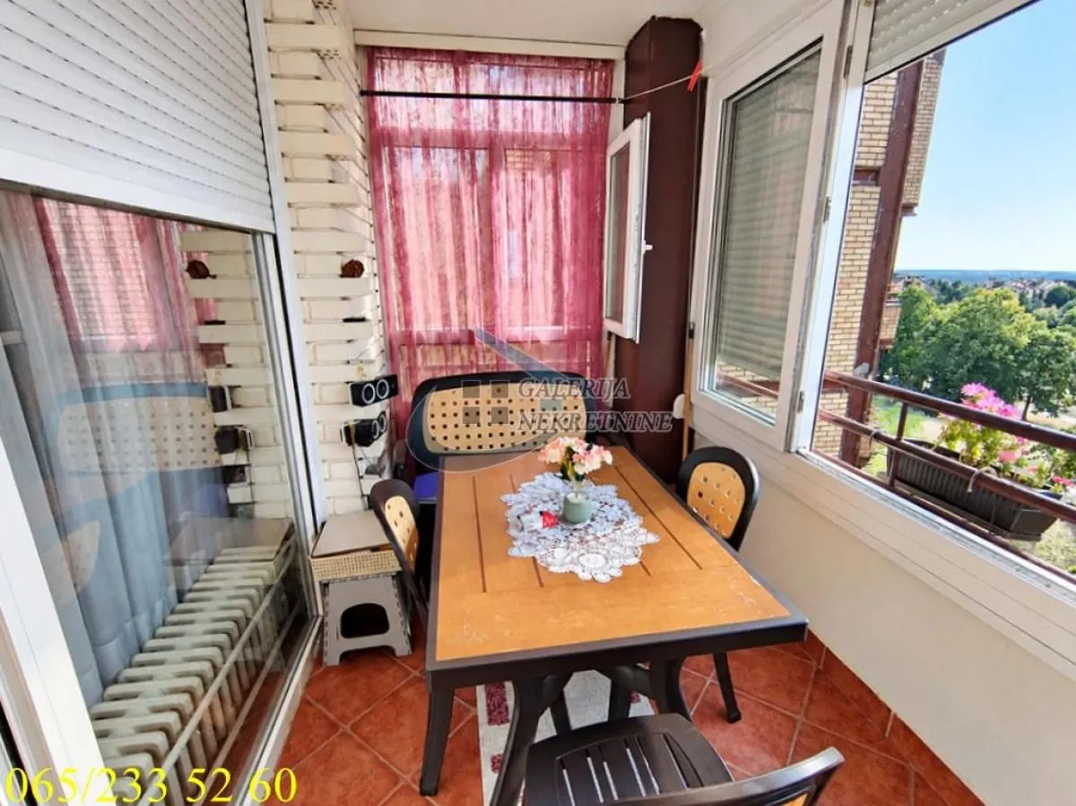 Zastakljena terasa sa trpezarijskim stolom i pogledom na okolinu.