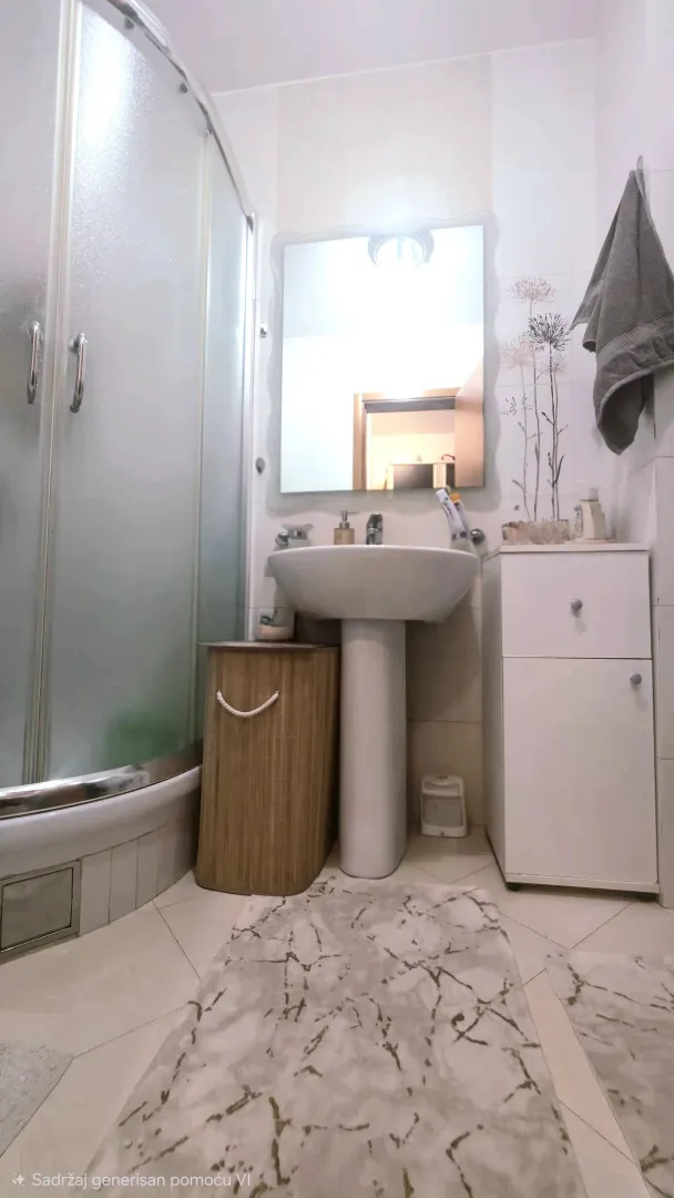 Small bathroom with a shower cabin, washbasin, and white storage units.