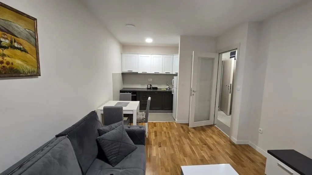 Living room with a sofa and dining area connected to the kitchen.