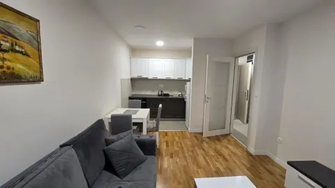 Living room with a sofa and dining area connected to the kitchen. - image 3