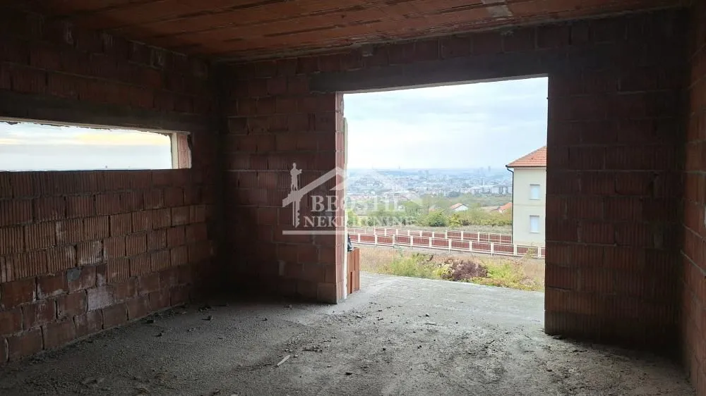 Pogled iz prostorije u sivoj fazi izgradnje sa ciglenim zidovima i otvorom prema spoljašnjosti.