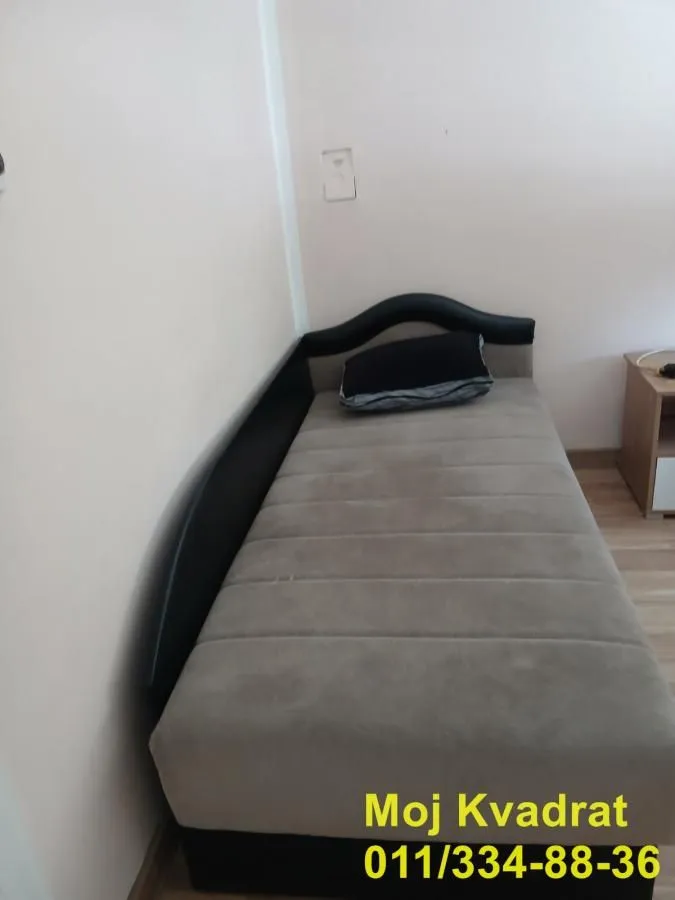 Single bed in a smaller part of the room with a nightstand.