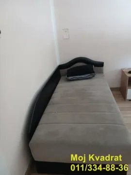 Single bed in a smaller part of the room with a nightstand. - image 11