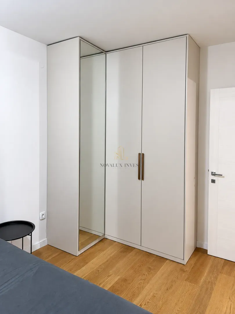 Bedroom with a built-in mirrored wardrobe and wooden flooring.