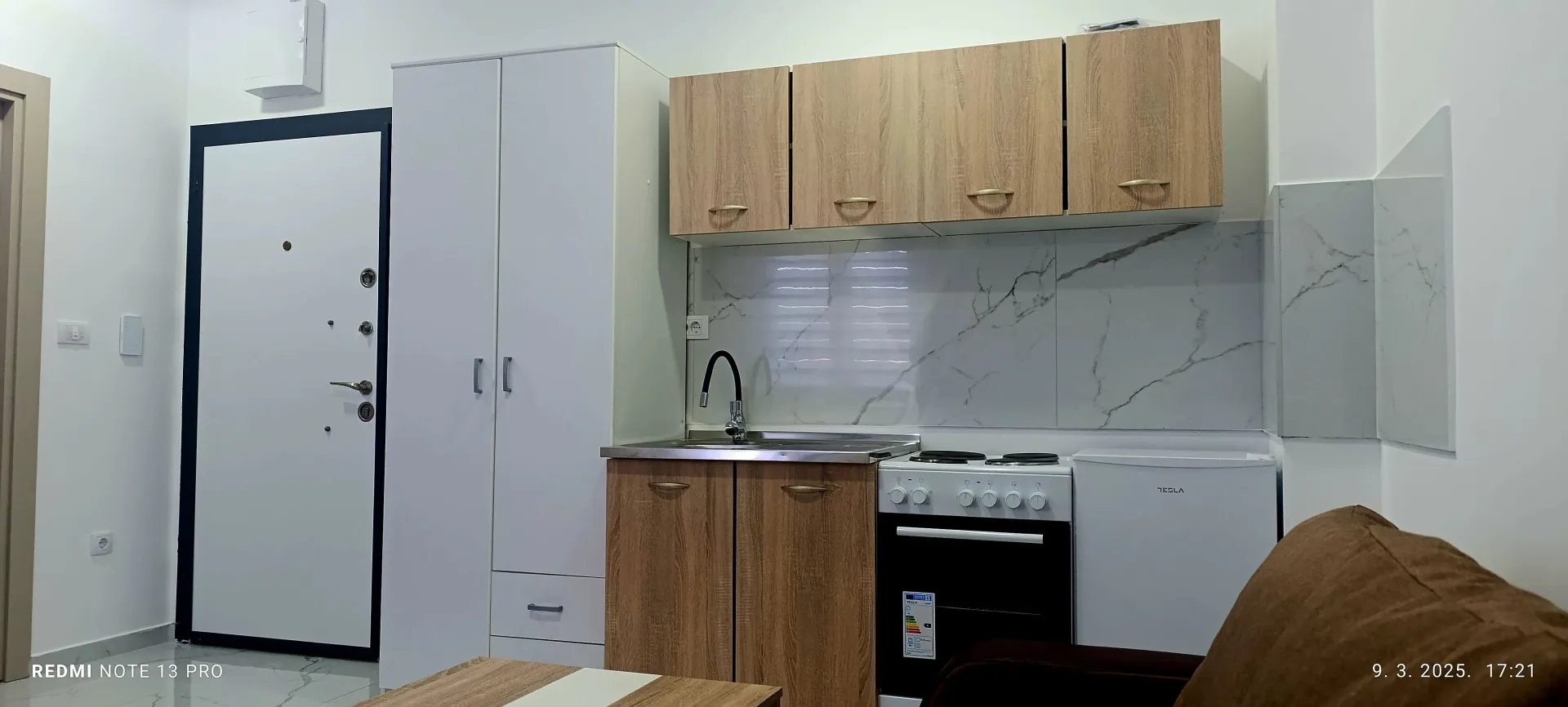 Small apartment kitchen with wooden cabinets and white appliances.