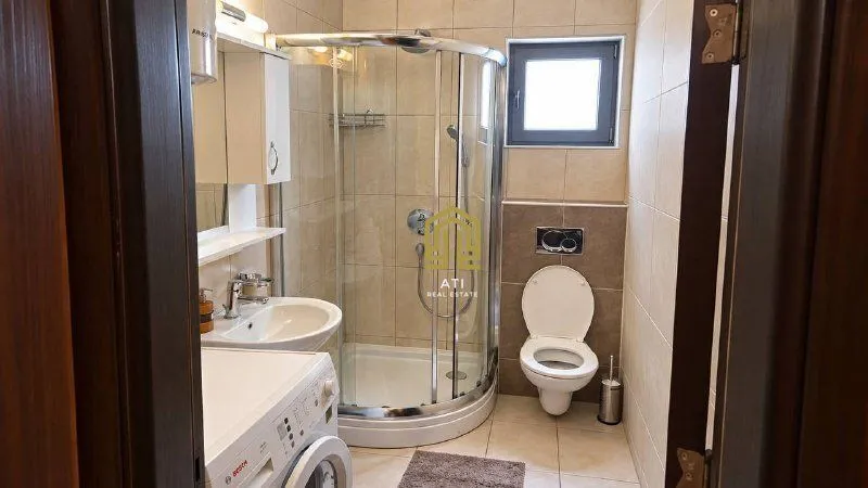 Moderno opremljeno kupatilo sa tuš kabinom i sanitarijama.