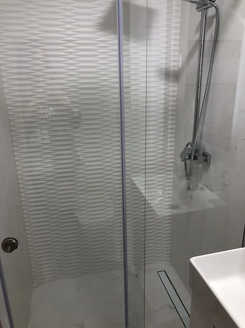 A modern shower cabin with glass doors in a bathroom.