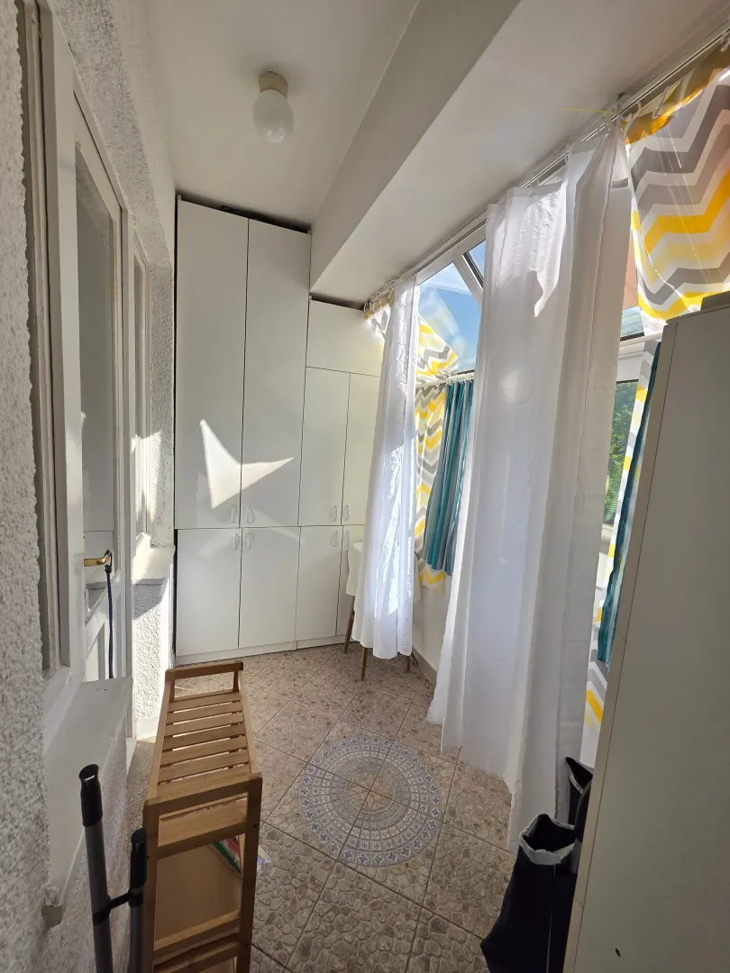Enclosed terrace with white cabinets and curtains.
