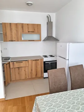 Manja kuhinja sa drvenim elementima i bijelim frižiderom u sklopu trpezarije. - image 3