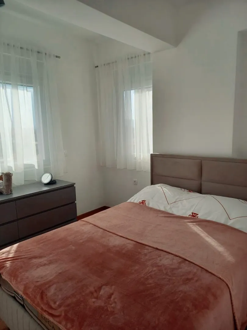 Bright bedroom with a double bed and windows with white curtains.