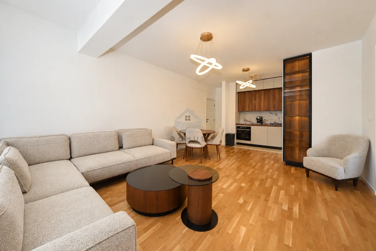 Modern living room with sofa, dining area, and fitted kitchen.