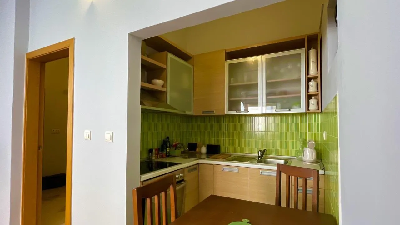 Small kitchen with wooden elements and green tiles.