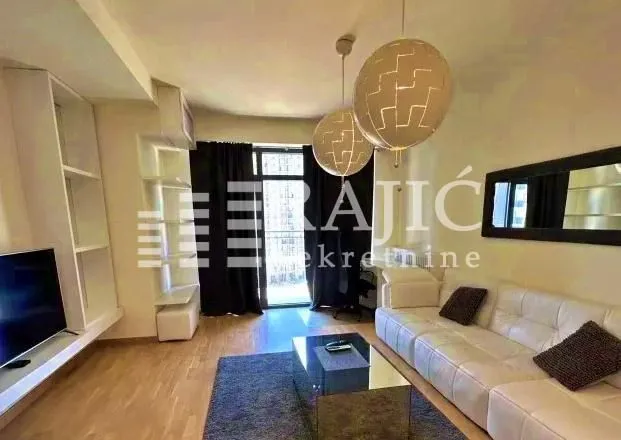 Living room with a white sofa, TV, and modern lighting.