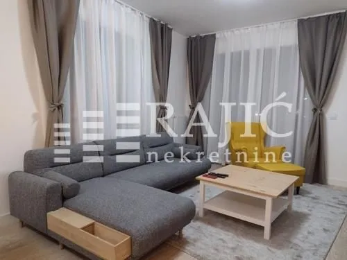 Living room furnished with a sectional sofa, coffee table, and armchair.