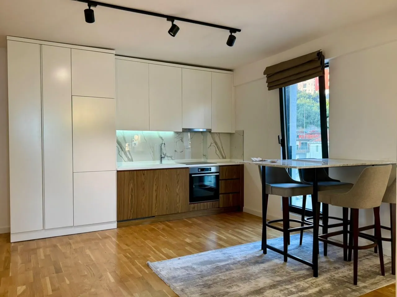 Modern kitchen with white and wooden elements and a dining table with chairs.