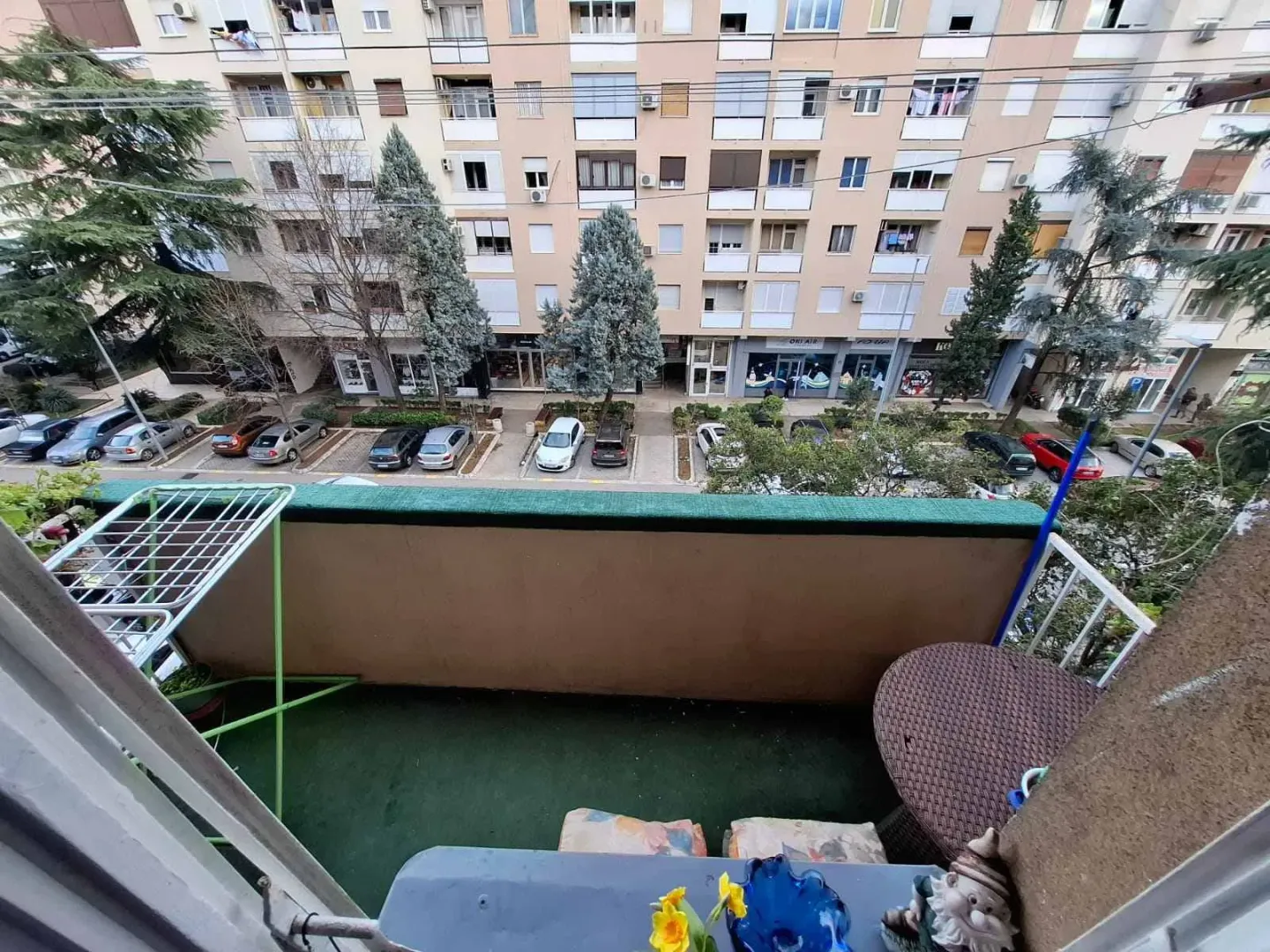 Pogled sa balkona na zgradu i parking.