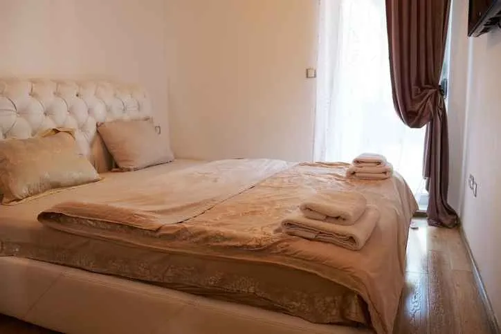 Spavaća soba sa bračnim krevetom i prozorom sa zavjesama.