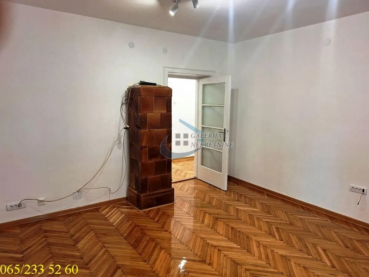 Empty room with wooden parquet flooring and a solid fuel stove.