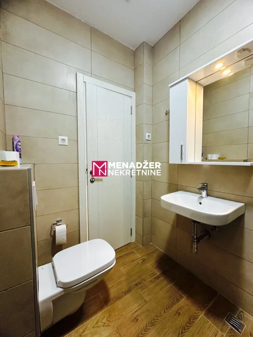 A neatly arranged bathroom with sanitary fixtures and white units.