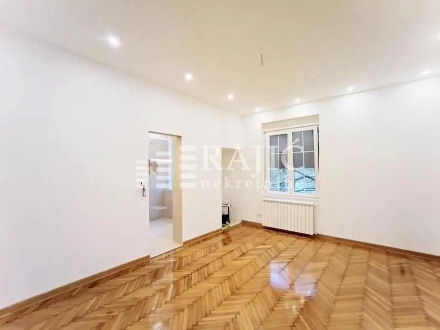 Empty room with parquet flooring and white walls.