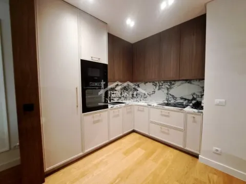 Modern corner kitchen with built-in appliances and wooden flooring. - image 8