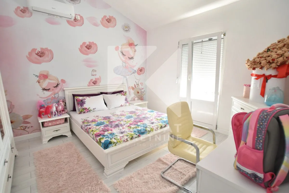 Children's bedroom with a double bed, desk, and wallpaper featuring floral and ballerina motifs.