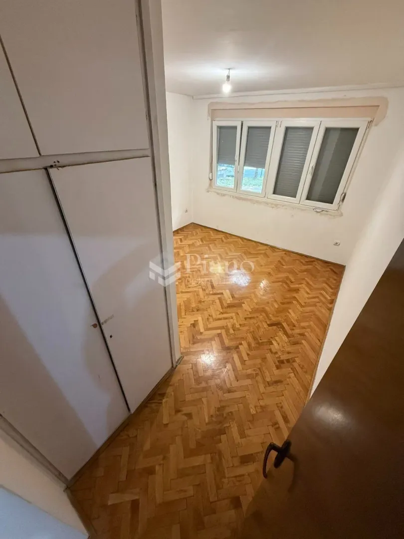 Empty room with parquet flooring and a built-in wardrobe.