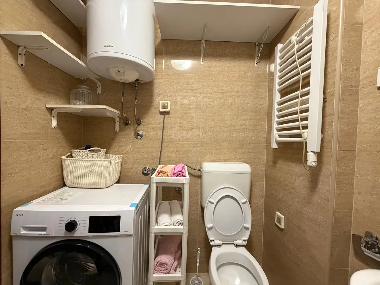 Small bathroom with a washing machine, water heater, and toilet.
