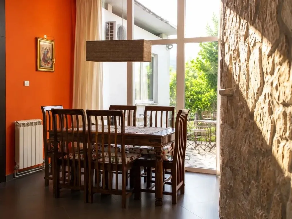 Dining area with a wooden table and chairs, next to a large glass wall.